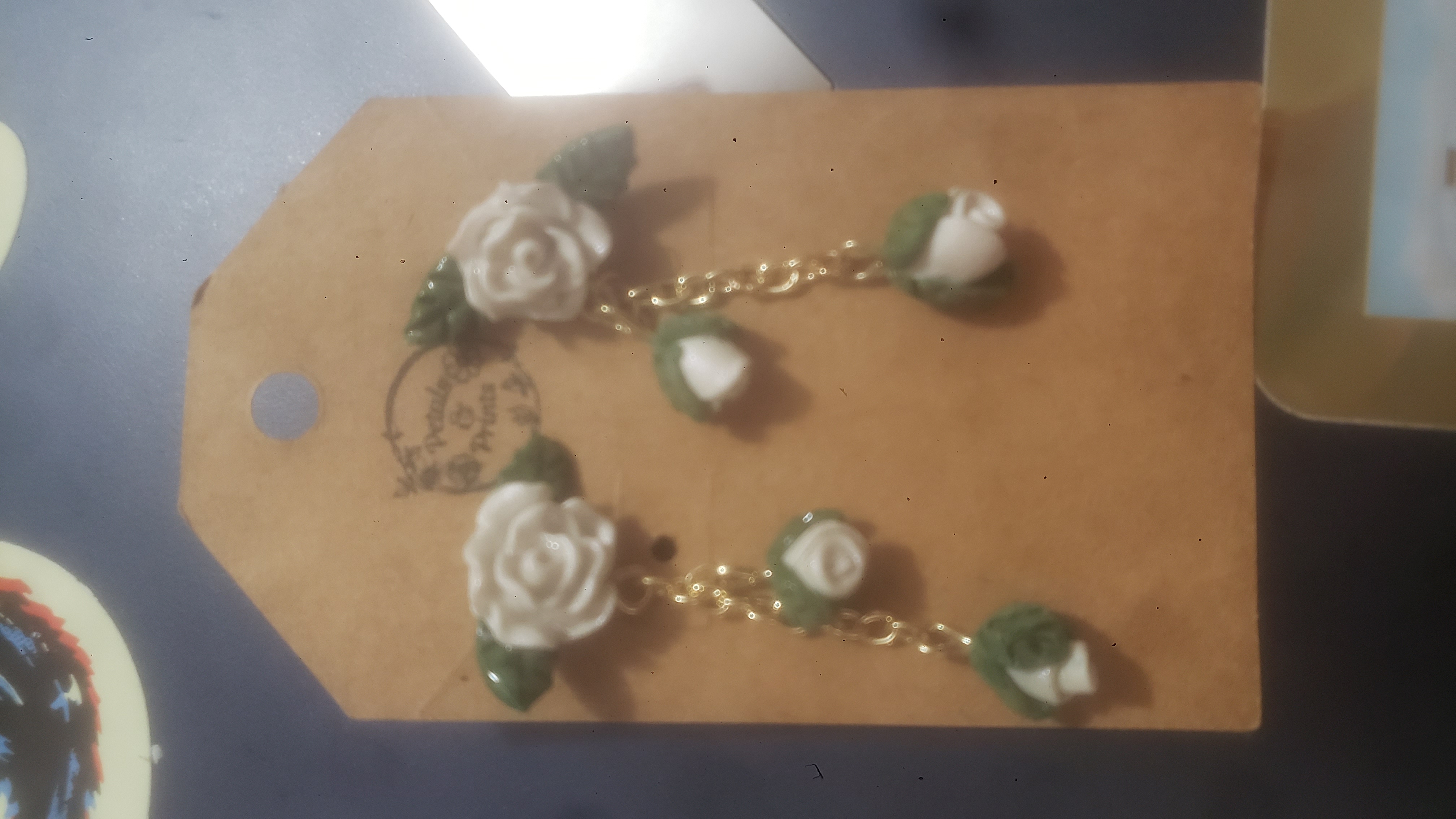 White rose earrings with a cardboard backing.